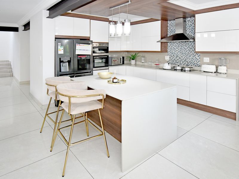 Modern kitchen featuring a central island, high-gloss cabinetry, integrated appliances, and a stylish mosaic tile backsplash with polished floor tiles.