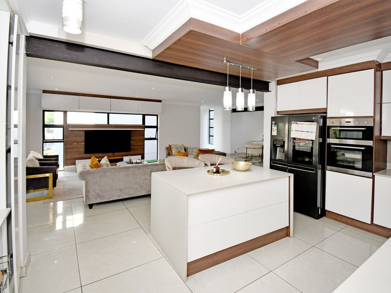 Modern open-plan living area featuring a sleek kitchen with a central island, built-in appliances, and high-quality finishes throughout the combined space.