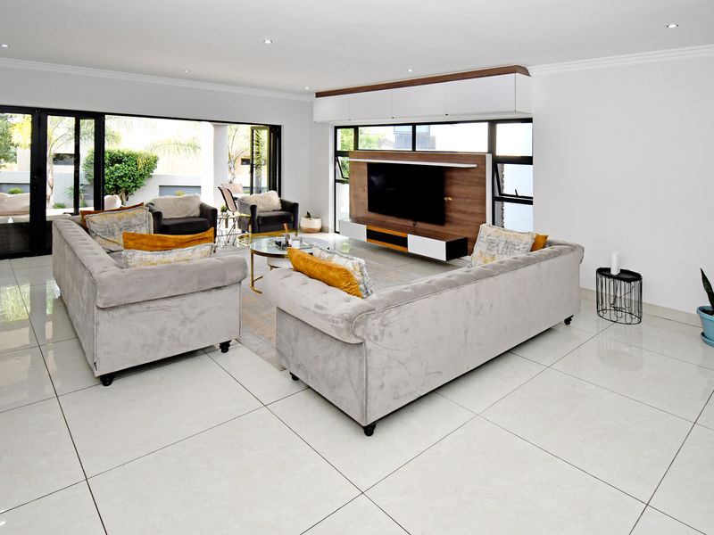 Spacious modern living room featuring large porcelain floor tiles, recessed lighting, and seamless indoor-outdoor flow through wide aluminium stacking doors.