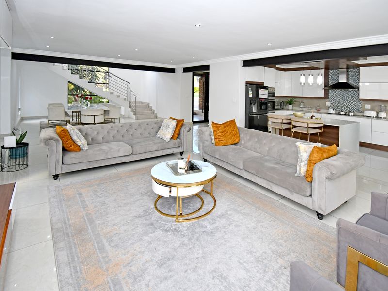 Spacious open-plan living area featuring a modern kitchen with island, sleek cabinetry, and a contemporary staircase leading to the upper level.