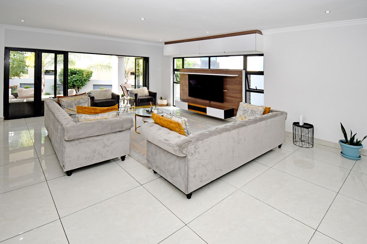 Spacious modern living room featuring large porcelain floor tiles, recessed lighting, and seamless indoor-outdoor flow through wide aluminium stacking doors.