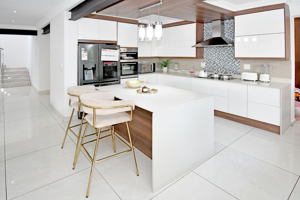 Modern kitchen featuring a central island, high-gloss cabinetry, integrated appliances, and a stylish mosaic tile backsplash with polished floor tiles.