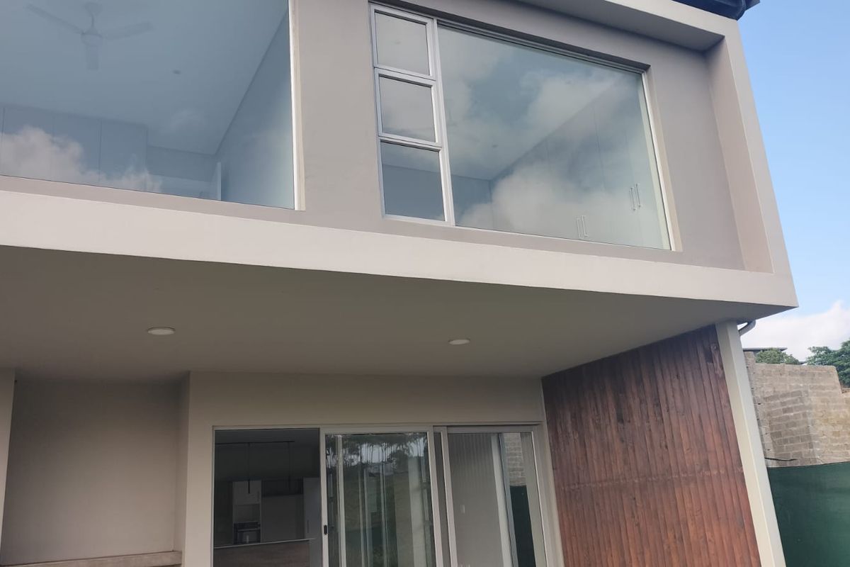 Modern rear elevation featuring large glass windows, sliding doors, and a stylish timber-clad accent wall, showcasing contemporary architectural design.