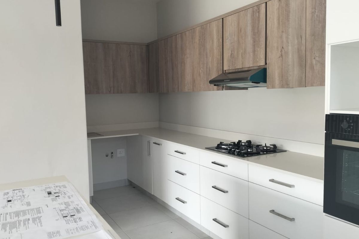 Modern kitchen featuring sleek white base cabinets, wood-grain upper cupboards, stone countertops, a gas hob, extractor fan, and a built-in oven.