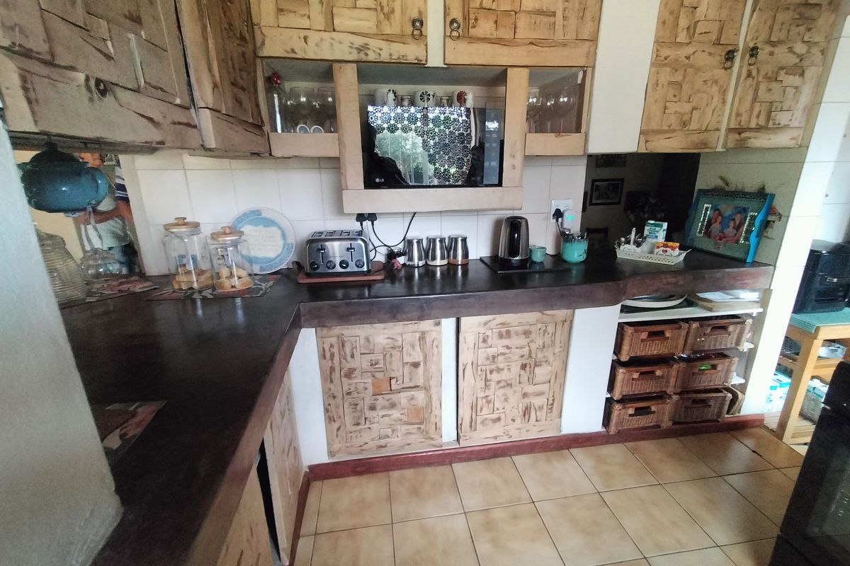 A functional kitchen featuring rustic wooden cabinetry, dark countertops, and tiled flooring, offering a traditional aesthetic with ample storage space.