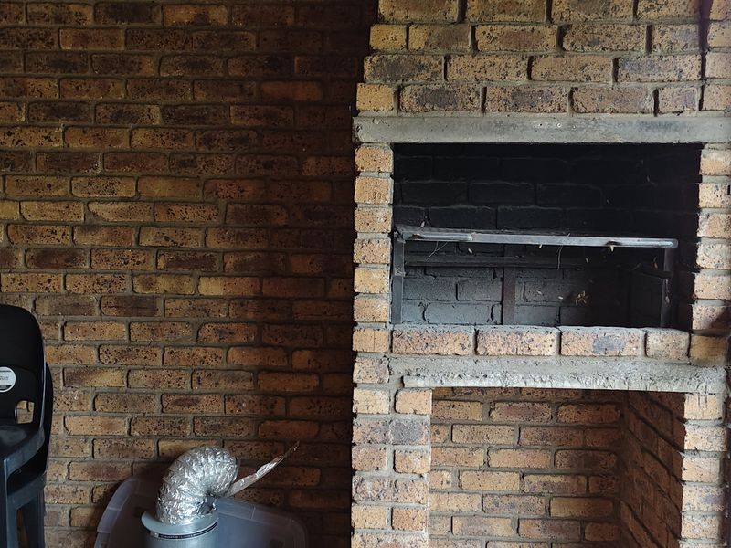 Outdoor patio area featuring a built-in brick braai and secure metal gate access.
