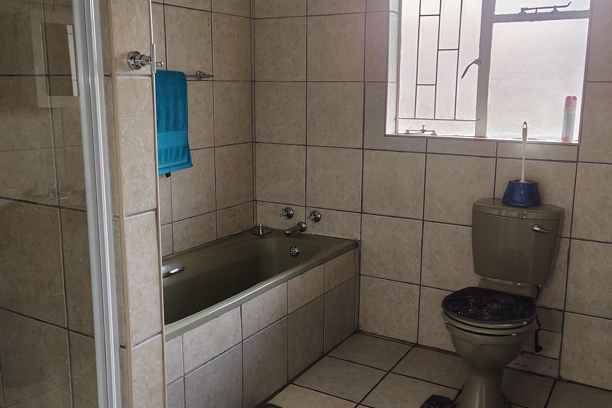 A dated bathroom featuring tiled walls and flooring, a bathtub, a separate shower enclosure, and a pedestal basin.