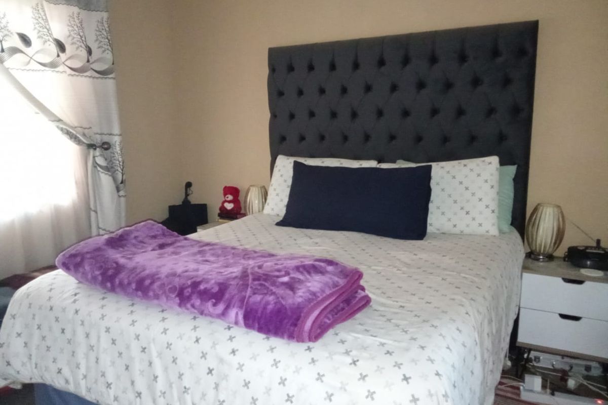 A standard bedroom featuring neutral wall paint and a window with curtains.