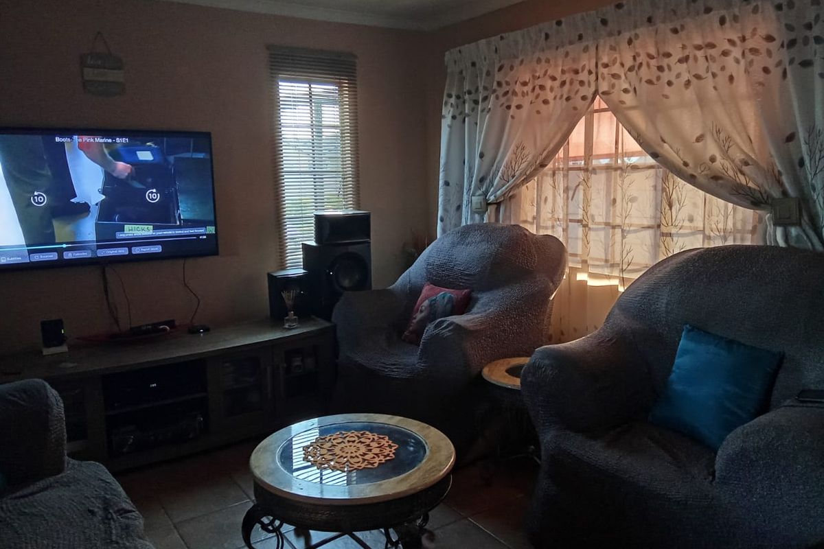 A cozy living room featuring tiled flooring and natural light through window blinds and curtains.