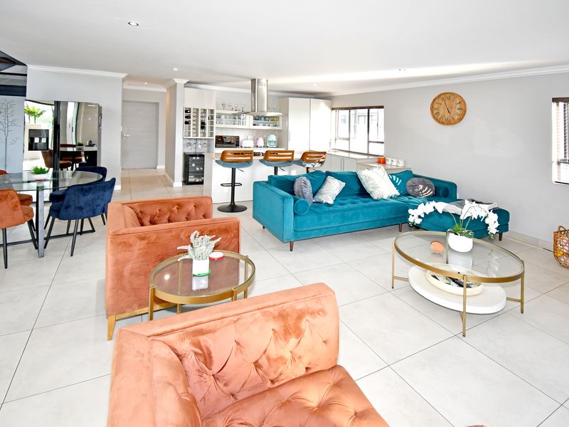 Spacious open-plan living area featuring a modern kitchen with island, tiled flooring, and integrated wine storage, seamlessly connecting to the dining and lounge spaces.