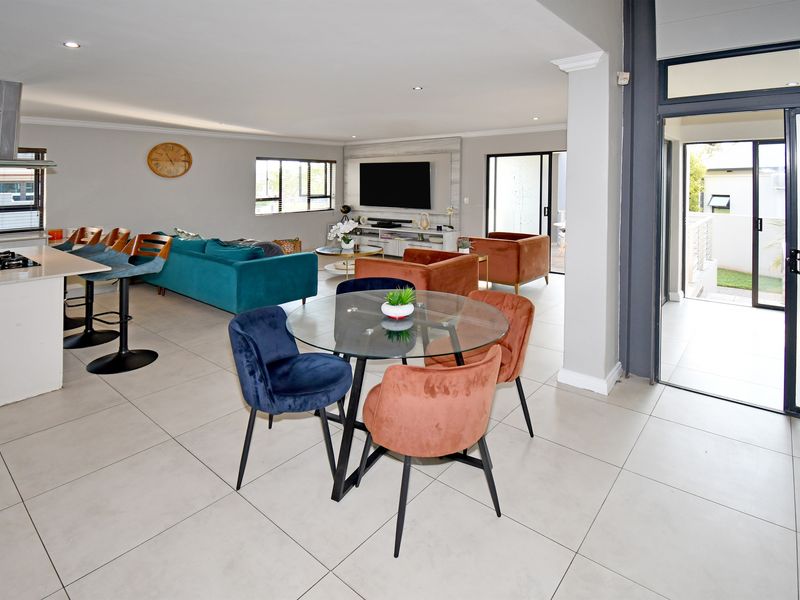Spacious open-plan living area featuring a modern kitchen with island, dining space, and seamless flow to the outdoor patio through large sliding glass doors.