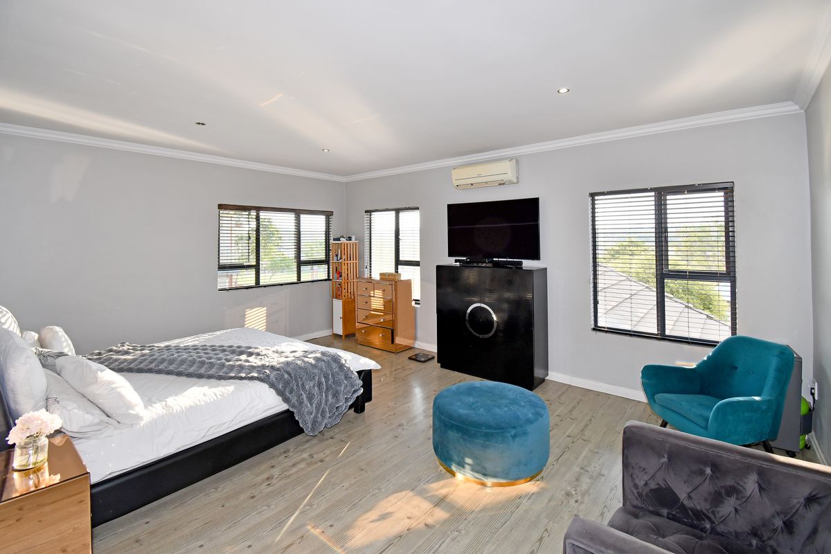 Spacious bedroom featuring laminate flooring, recessed downlighting, split-system air conditioning, and large windows with venetian blinds.