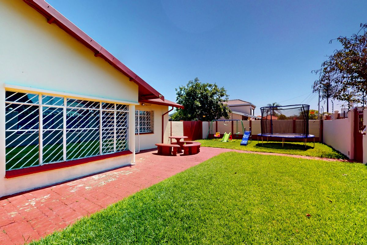 A private rear garden featuring a paved patio area, well-maintained lawn, and secure perimeter walling.