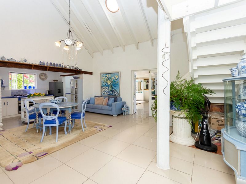 Spacious open-plan living and dining area featuring a vaulted ceiling with exposed beams, a skylight, and an integrated kitchen with tiled flooring.