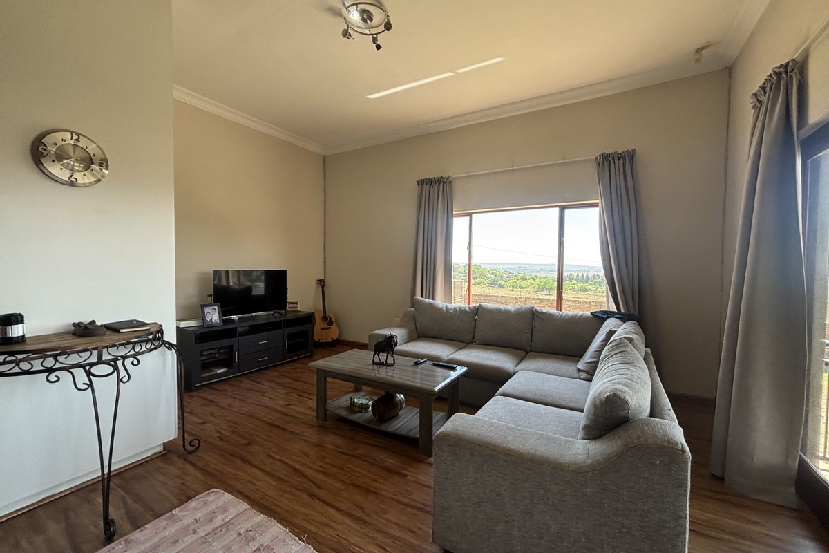 A spacious living room featuring wood-look flooring, large windows with natural light, and direct access to an outdoor area.