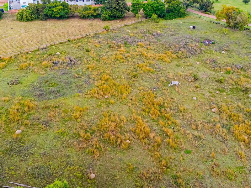 An aerial view of a vacant residential plot featuring open grassland and perimeter fencing, suitable for future development.