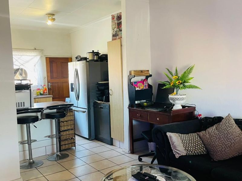 Open-plan living area featuring tiled flooring and a breakfast bar, seamlessly connecting the kitchen and lounge space.