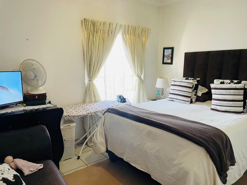 A functional bedroom featuring tiled flooring and window treatments, offering a comfortable space for rest.