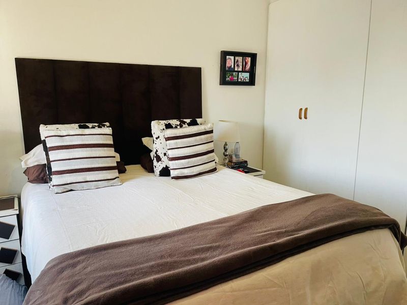 A functional bedroom featuring a built-in wardrobe and neutral wall finishes, offering a comfortable space for rest.