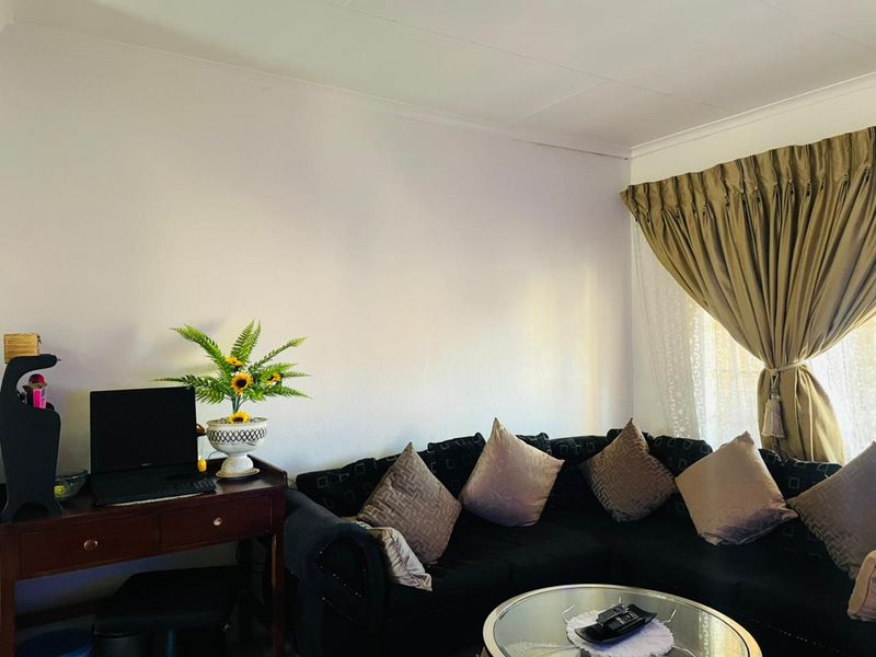 A living room area featuring neutral walls, coved ceiling detailing, and window treatments.