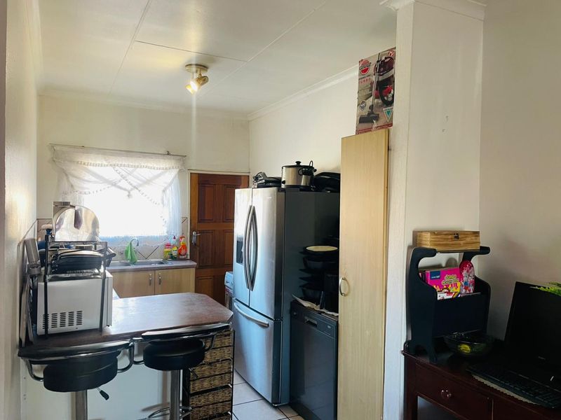 A compact kitchen featuring functional cabinetry, a stainless steel sink, and tiled flooring, offering potential for a modern renovation.