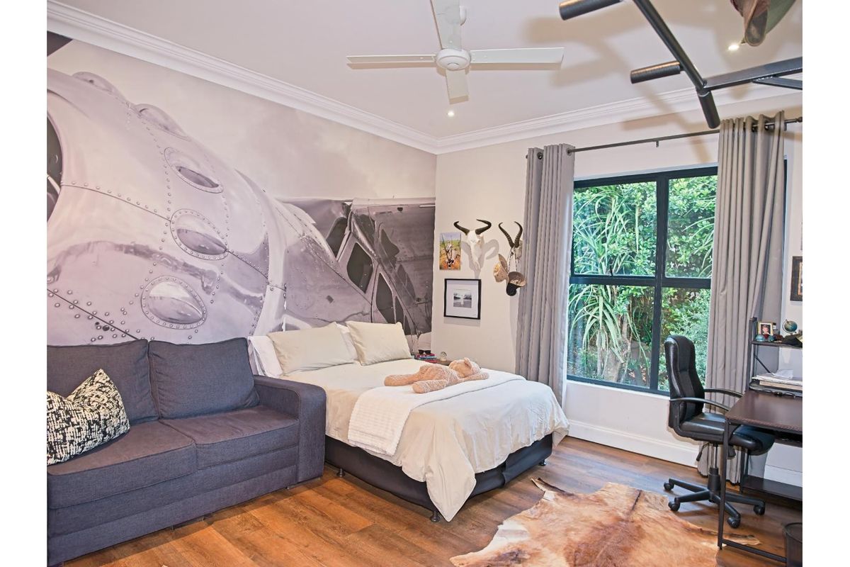 A well-maintained bedroom featuring hardwood flooring, crown molding, recessed lighting, a ceiling fan, and a large window with garden views.