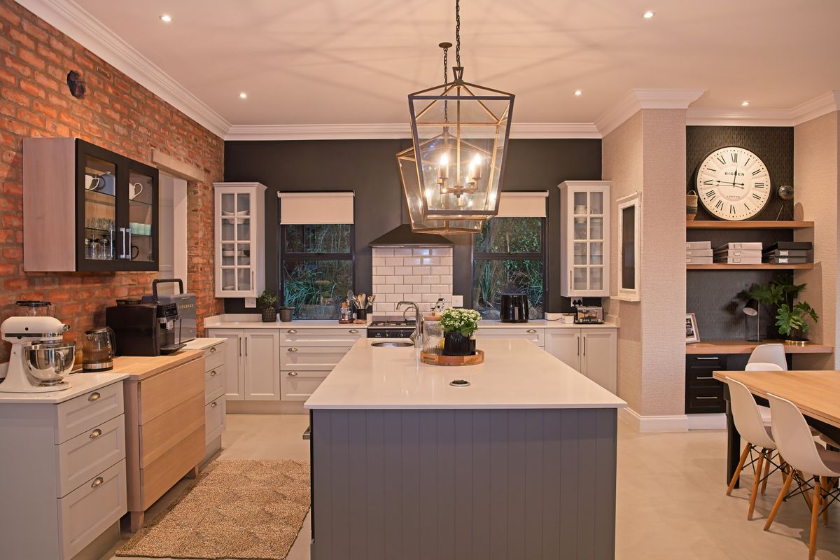 Modern kitchen featuring a large central island, quartz countertops, exposed brick accents, and high-quality cabinetry with integrated lighting and built-in shelving.