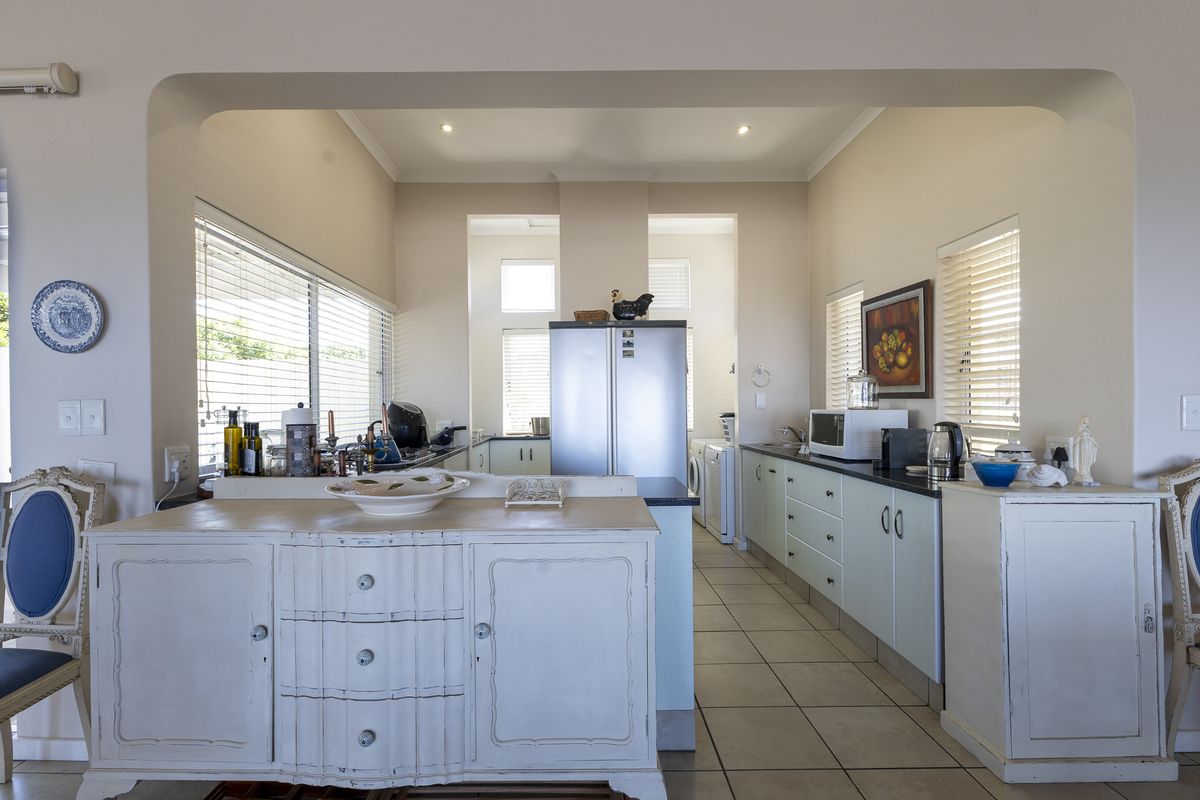 A functional kitchen featuring built-in cabinetry, stone countertops, and tiled flooring, offering a practical layout with ample natural light from multiple windows.
