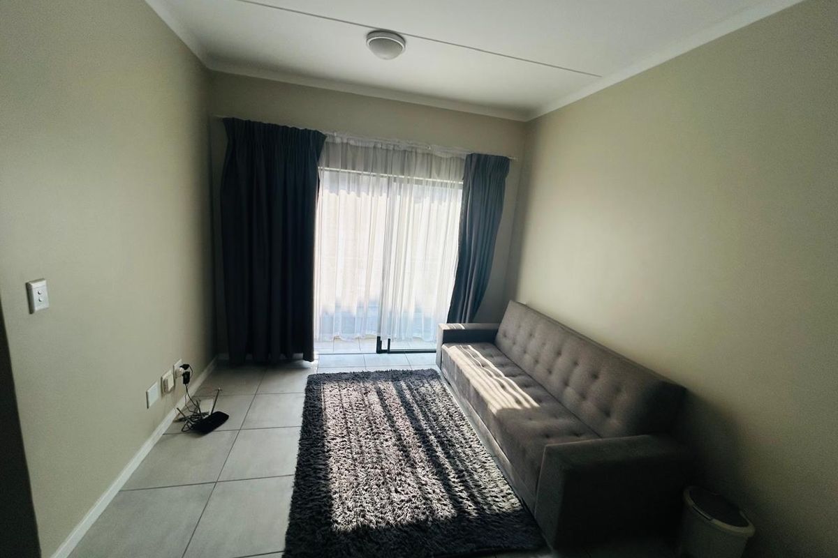 A living room featuring neutral tiled flooring and a sliding glass door that provides access to an outdoor area.