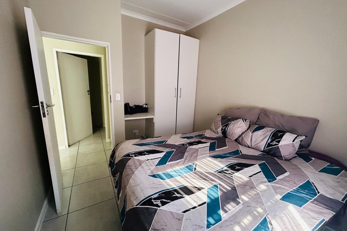 A bedroom featuring tiled flooring, a built-in wardrobe with an integrated vanity area, and coved ceiling detailing.
