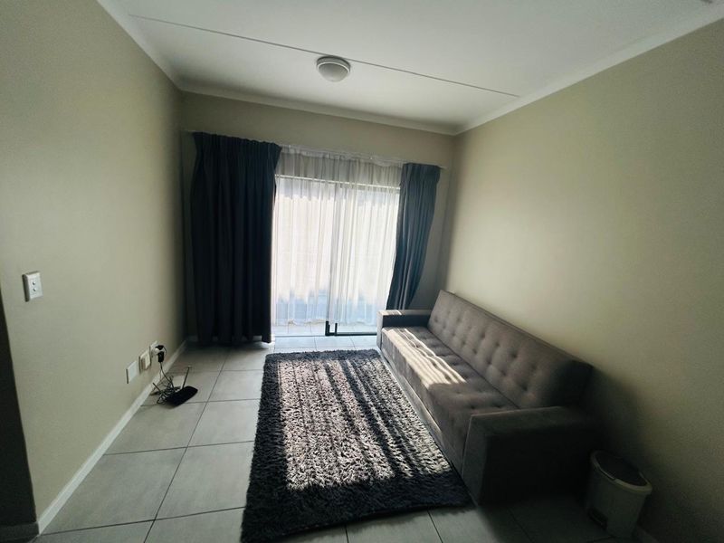 A living room featuring neutral tiled flooring and a sliding glass door that provides access to an outdoor area.