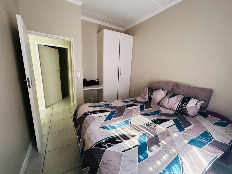 A bedroom featuring tiled flooring, a built-in wardrobe with an integrated vanity area, and coved ceiling detailing.