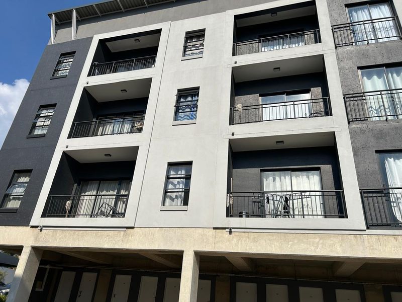 A modern multi-story apartment building facade featuring stacked balconies with metal railings and sliding glass doors.