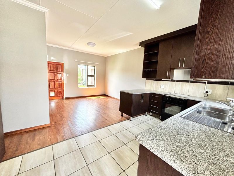 Open-plan living area featuring a kitchen with granite countertops, dark wood cabinetry, and a seamless transition to the adjacent living space with laminate flooring.