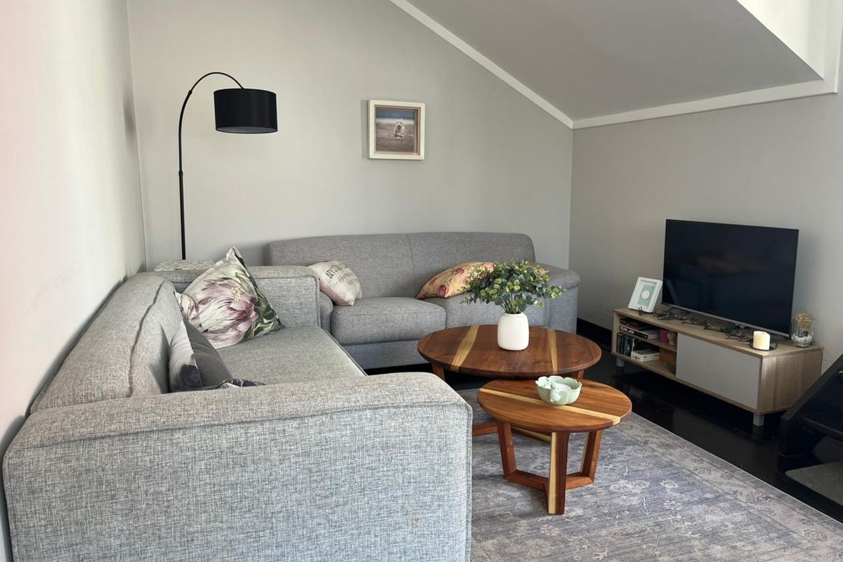 A cozy living room featuring a sloped ceiling and dark timber flooring, creating a comfortable and inviting atmosphere.