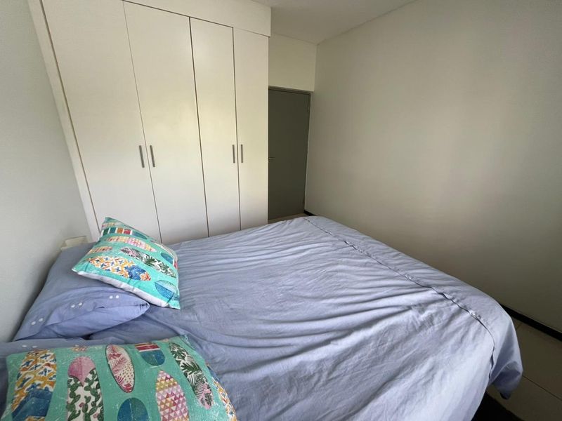 A functional bedroom featuring a white built-in wardrobe with clean lines and neutral wall finishes.