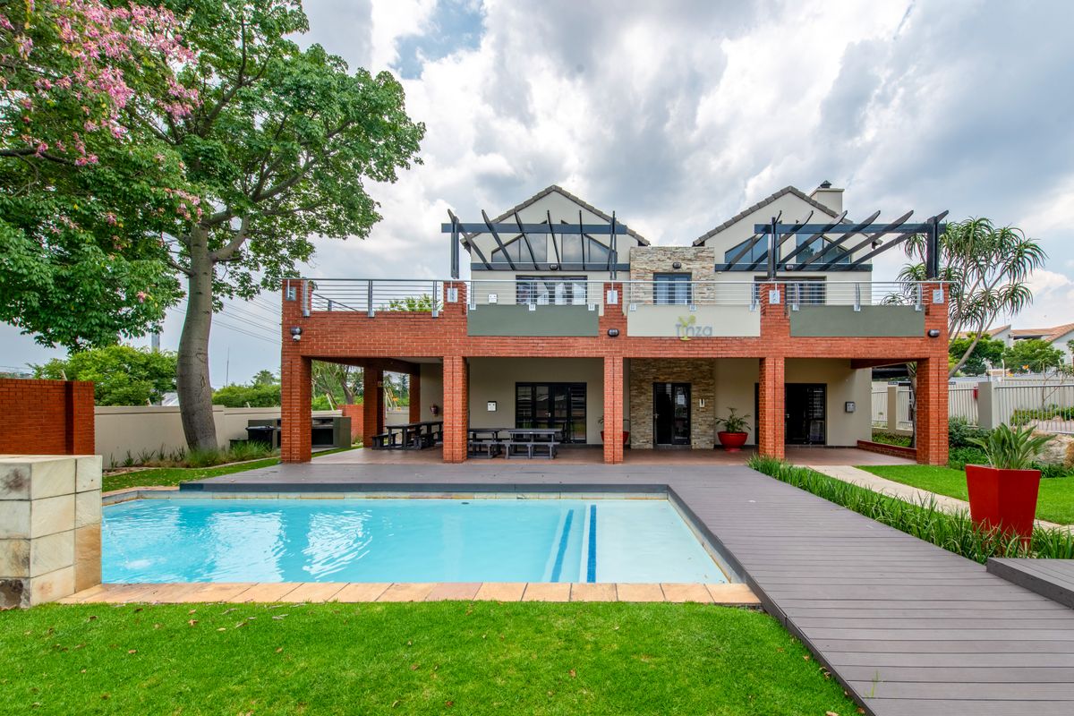 Rear view of the apartment complex featuring a swimming pool, timber decking, covered patio area, and a balcony with pergola structures.