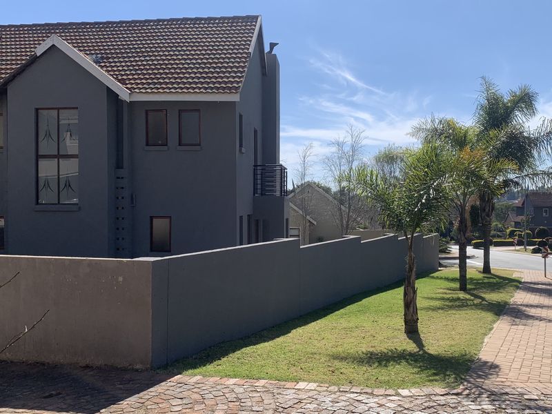 A view of the front exterior of a modern double-story house featuring a grey facade, tiled roof, and a surrounding boundary wall.
