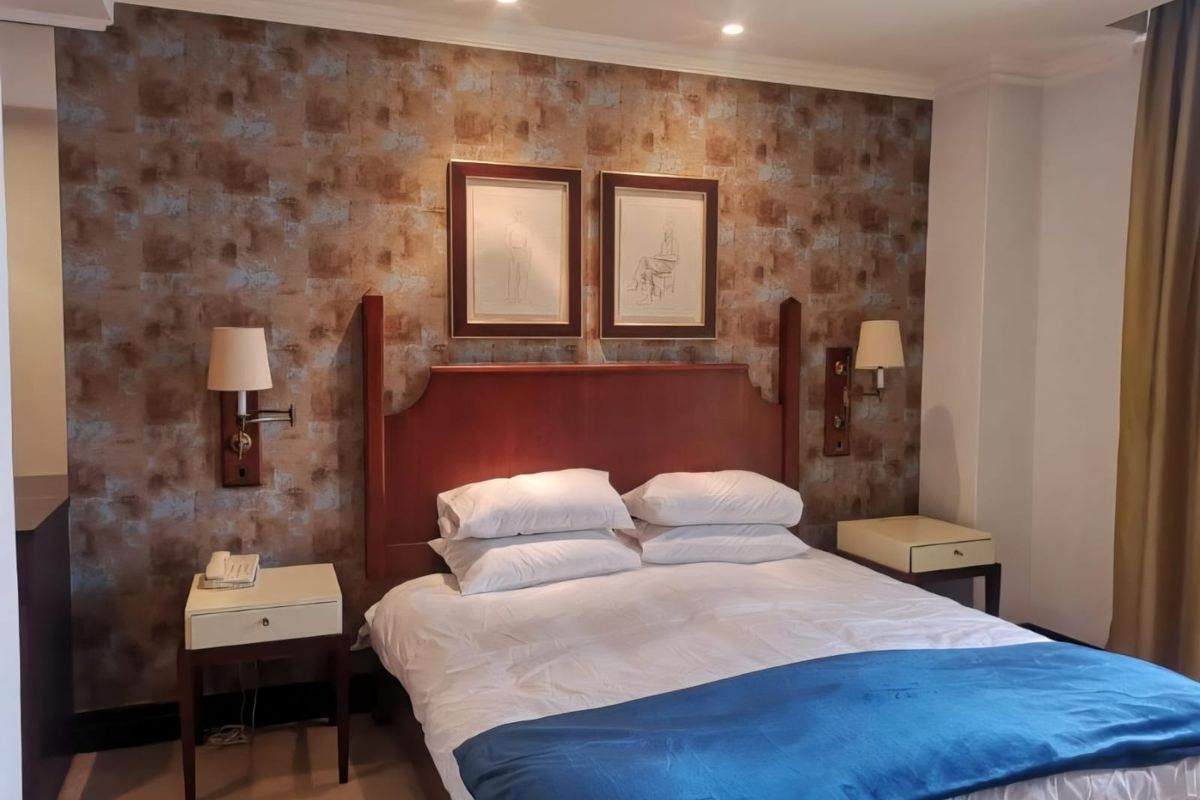 A well-maintained bedroom featuring a decorative feature wall, built-in headboard, and integrated wall-mounted lighting fixtures.