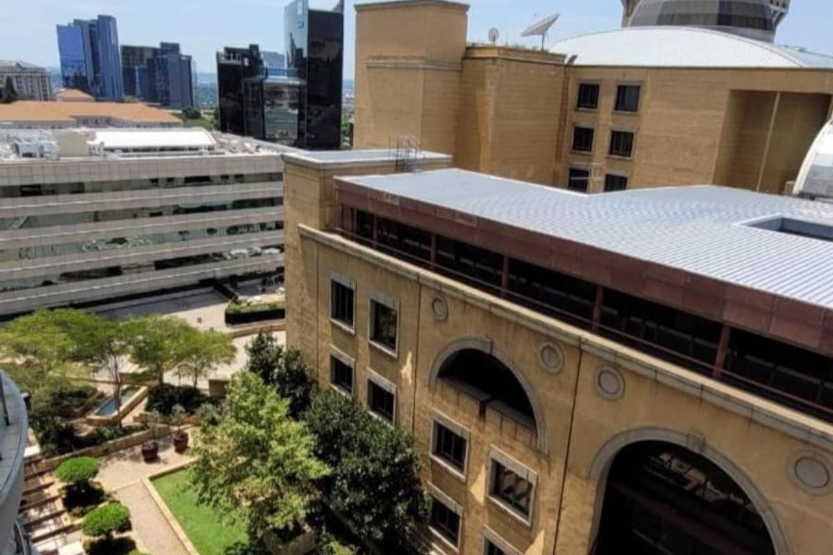 Elevated aerial view overlooking a landscaped courtyard with a central fountain and surrounding urban commercial buildings.