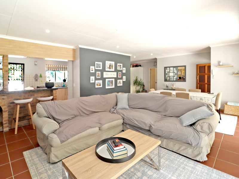 Open-plan living and dining area featuring tiled flooring, a brick breakfast bar, and recessed lighting, creating a functional and connected family space.