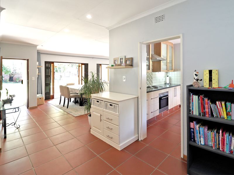 Open plan living area featuring tiled floors, recessed lighting, and a direct view into the adjacent kitchen and outdoor patio space.