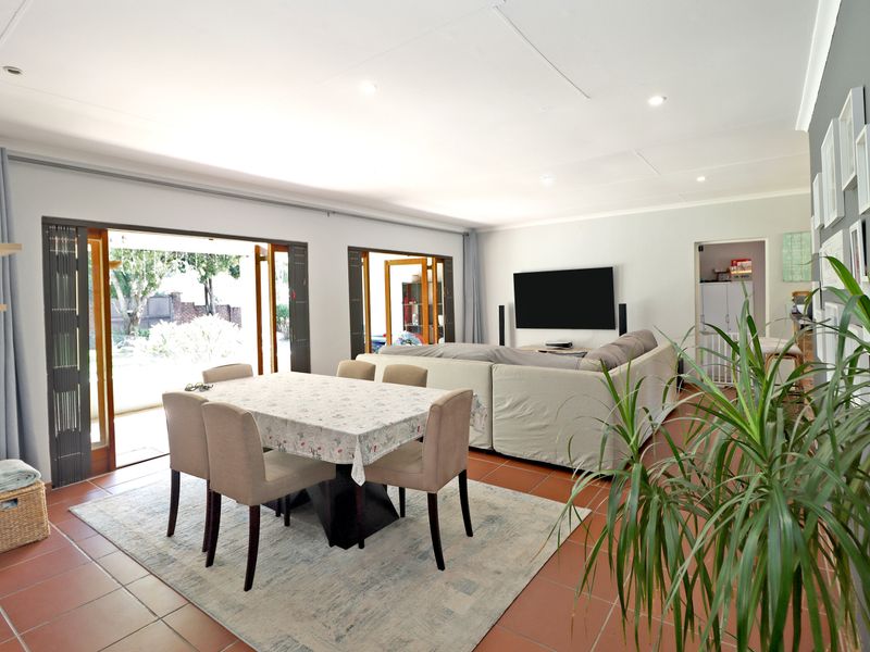 Spacious open-plan living and dining area featuring tiled flooring, recessed lighting, and large folding glass doors providing seamless access to the outdoor space.