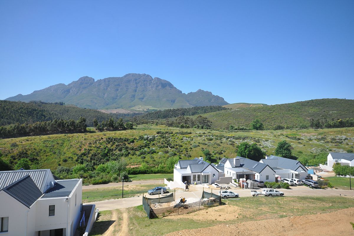 Elevated view of a modern residential estate featuring contemporary homes with pitched roofs, set against a scenic mountain landscape.