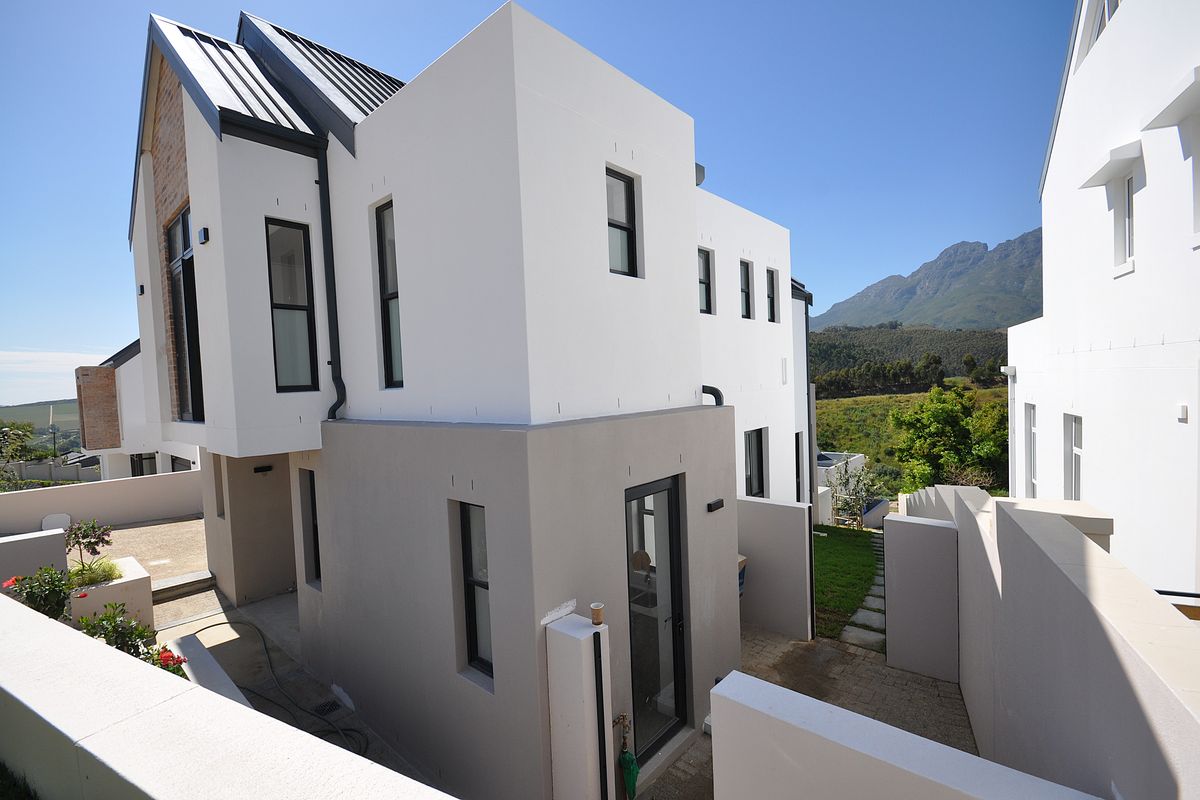 Modern multi-level residential exterior featuring clean architectural lines, contemporary finishes, and scenic mountain views in a well-maintained estate setting.