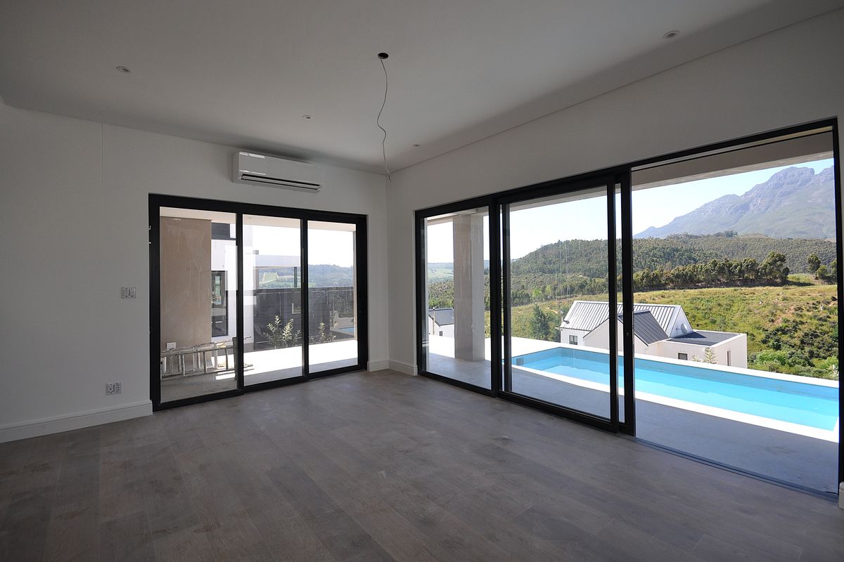 Spacious living area featuring large sliding glass doors that open to a patio and swimming pool, offering scenic mountain views.