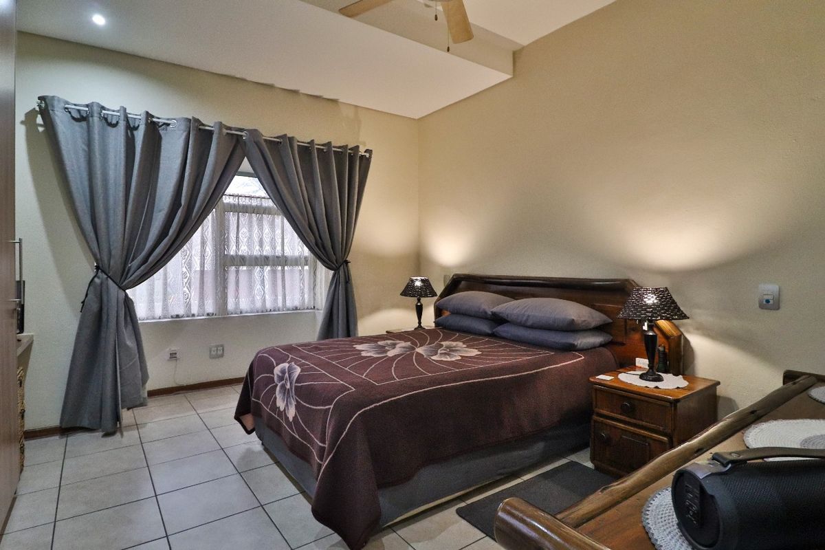 A comfortable bedroom featuring tiled flooring, a ceiling fan, and built-in wardrobe storage, offering a functional and well-maintained living space.