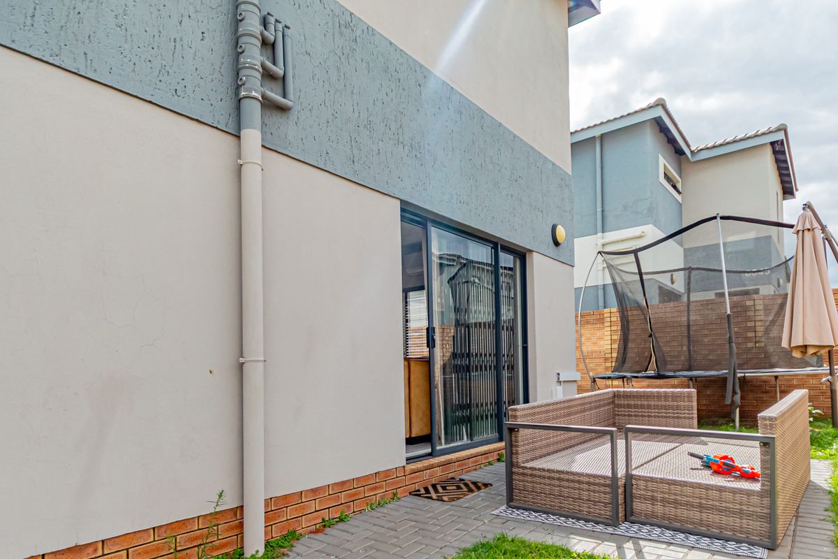 Rear exterior view of the property featuring a sliding glass door, paved patio area, and brick boundary wall.