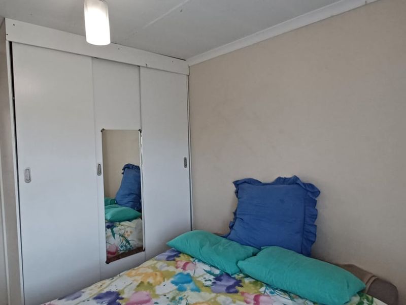 A bedroom featuring a built-in wardrobe with a central mirror, leading to an adjacent bathroom.