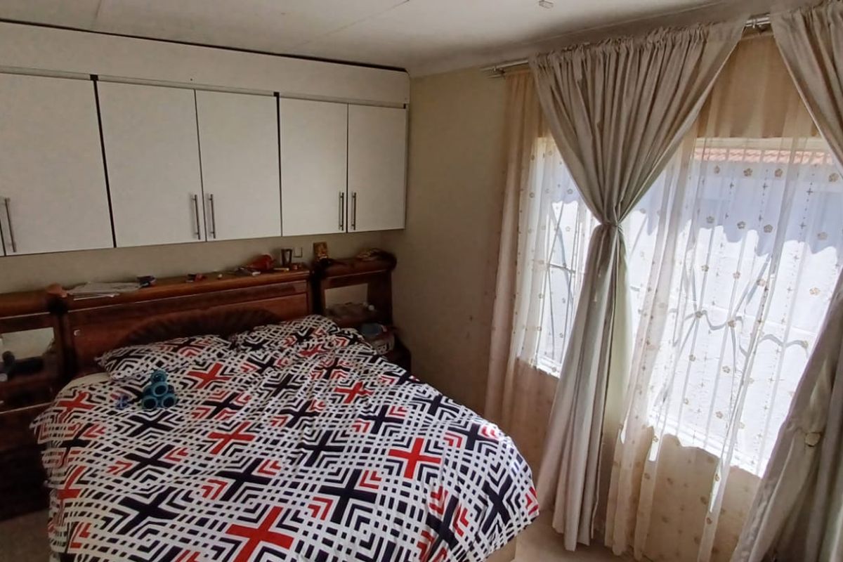 A bedroom featuring built-in cupboards and security bars on the windows, requiring cosmetic updates to improve the overall condition and appeal.